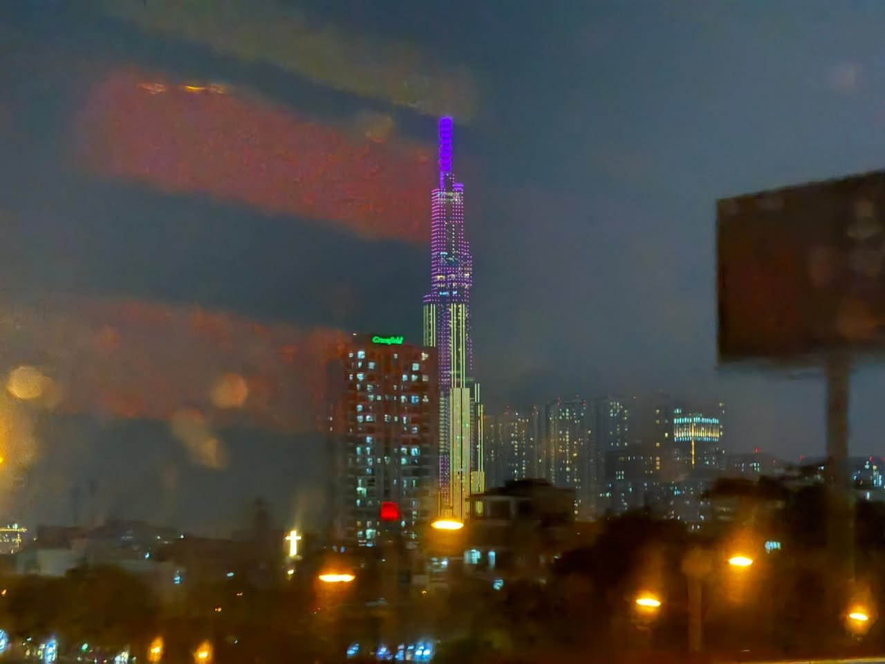 Landmark 81, lit purple, through a rainy window.