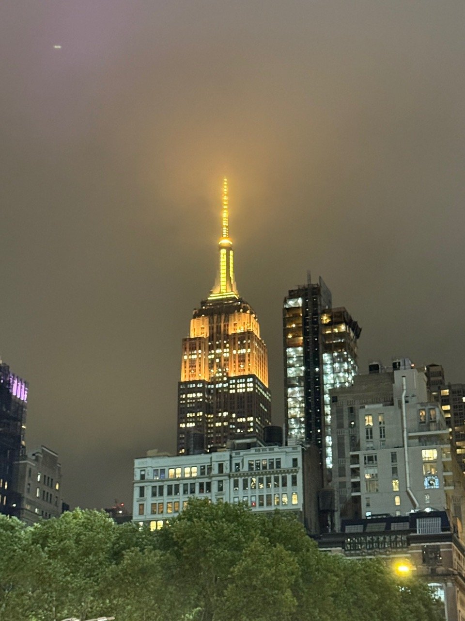 The Empire State Building, lit gold in the fog.